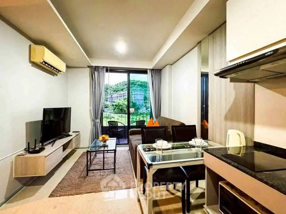 Modern living room with balcony view, sleek furniture, and open kitchen layout.