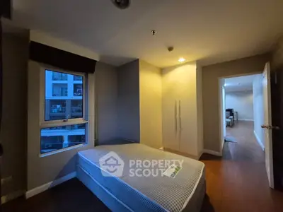 Cozy bedroom with single bed and built-in wardrobe, featuring a window view of modern apartment complex.