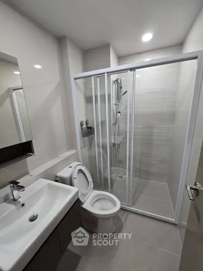 Modern bathroom with sleek fixtures and glass shower enclosure in a contemporary apartment.
