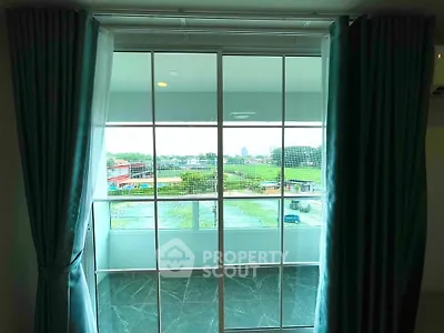 Spacious balcony with sliding glass doors offering a scenic view of lush greenery.
