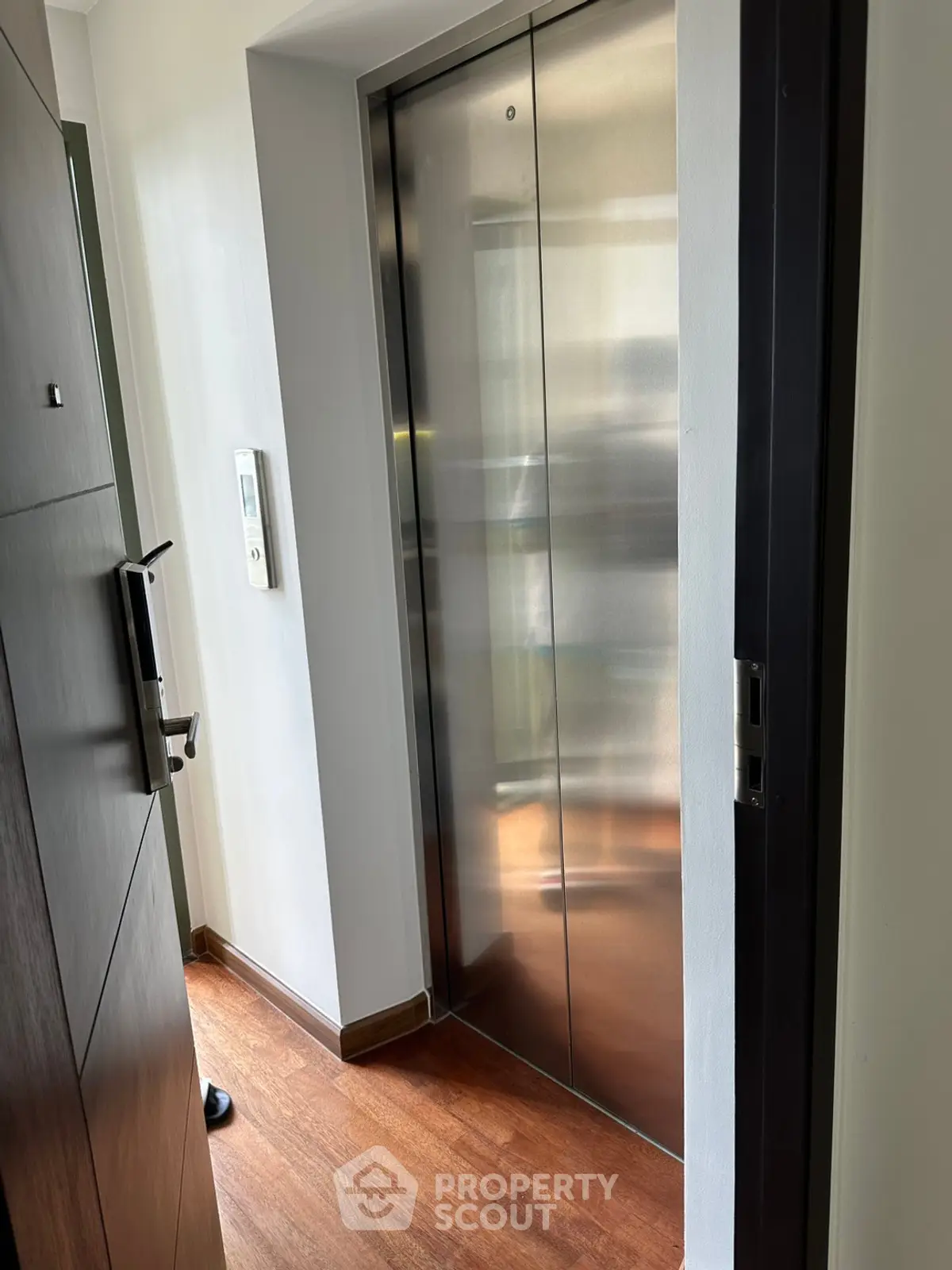 Modern apartment elevator with sleek metal doors and wooden flooring