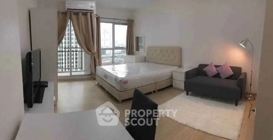 Modern studio apartment with cozy living area and large windows offering city views.