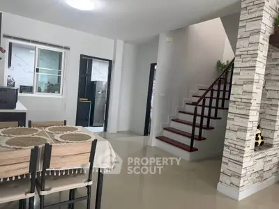 Modern dining area with staircase and open kitchen layout in a stylish home interior.