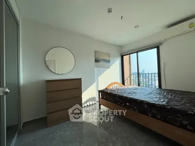 Bright bedroom with city view, featuring a wooden bed, dresser, and large window for natural light.