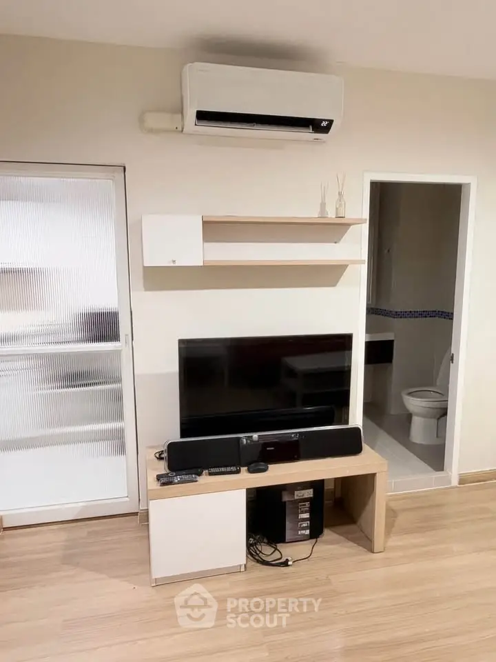 Modern living room with air conditioning and entertainment center, featuring sleek wooden flooring and minimalist decor.