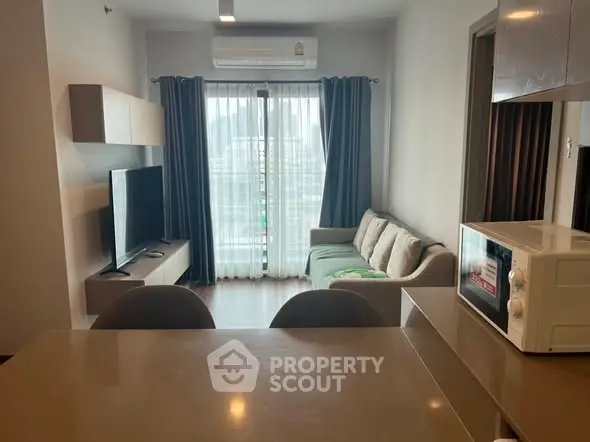 Modern living room with sleek furniture and large window, featuring a cozy sofa and entertainment setup.