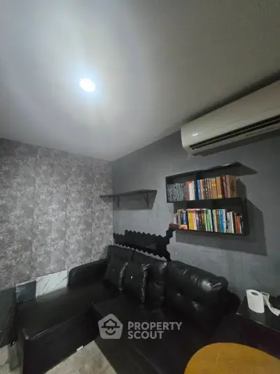 Cozy living room with black leather sofa and wall-mounted bookshelves