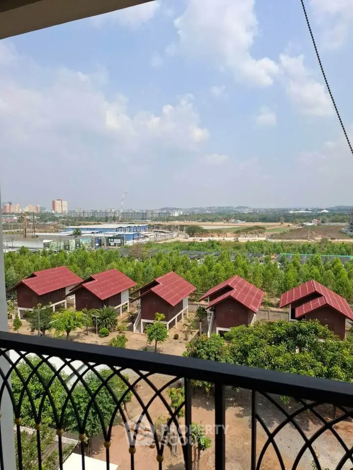 Scenic view from balcony overlooking lush greenery and charming red-roofed houses.