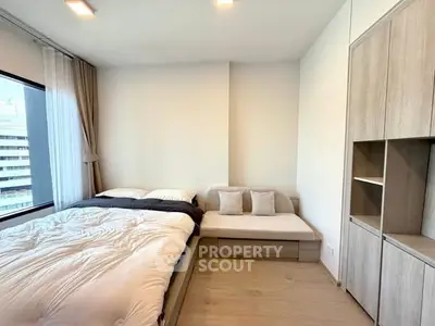 Modern bedroom with large window and built-in storage in a stylish apartment.