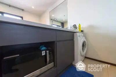 Modern kitchen with washing machine and microwave in sleek cabinetry