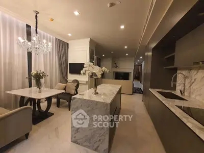 Luxurious open-layout kitchen and dining area with marble countertops and elegant chandelier.