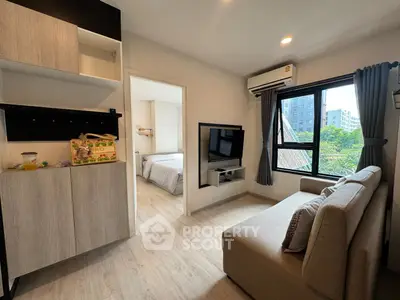 Modern living room with cozy sofa and wall-mounted TV, leading to a bright bedroom with large windows.