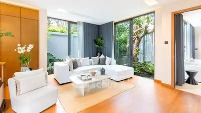 Luxurious living room with modern decor and garden view, featuring elegant white furniture and natural light.