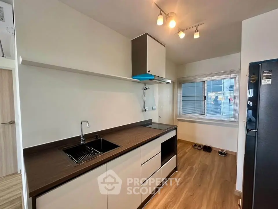 Modern kitchen with sleek cabinetry and wooden flooring, featuring a minimalist design and ample natural light.
