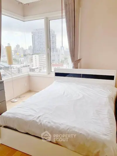 Bright bedroom with city view and modern furnishings in high-rise apartment.