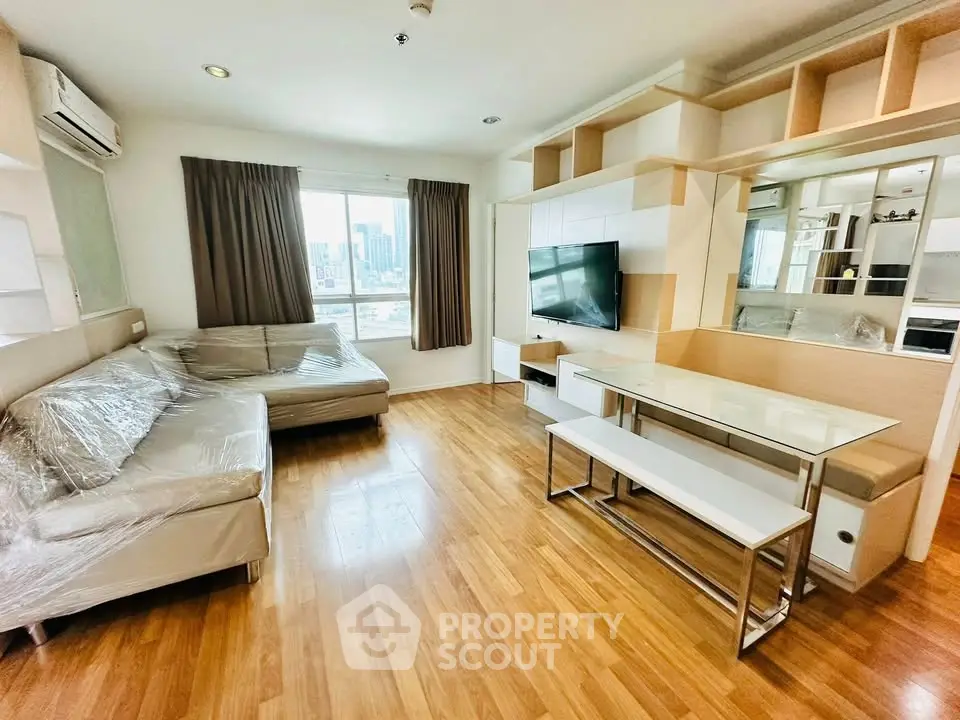 Spacious modern living room with city view, featuring sleek furniture and wooden flooring.