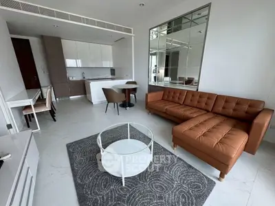 Modern living room with open kitchen, stylish furniture, and large mirror accent wall.