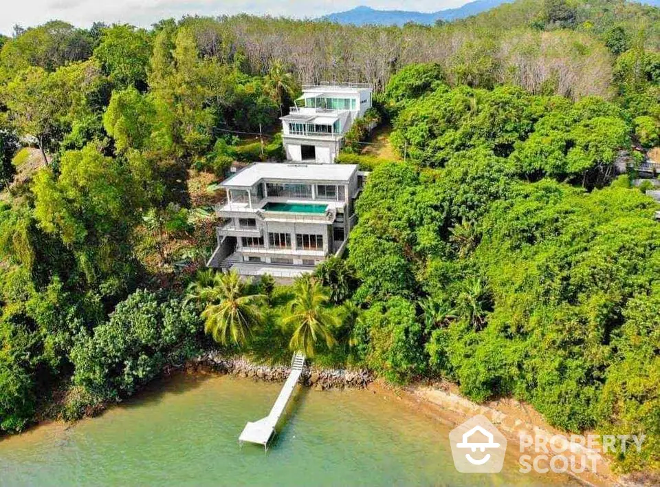 Stunning beachfront property with lush greenery and private dock, offering breathtaking views and luxury living.