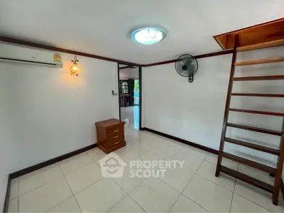 Spacious living area with gleaming tiled floors, elegant wooden staircase, and ample natural light, perfect for modern living.