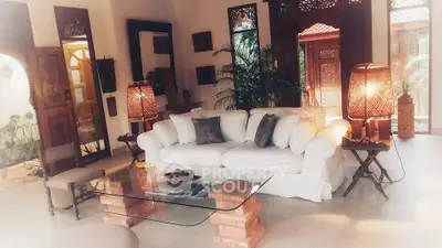 Charming living room with elegant decor and natural light, featuring a cozy white sofa and stylish glass coffee table.