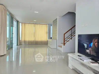 Spacious modern living room with large windows and sleek staircase