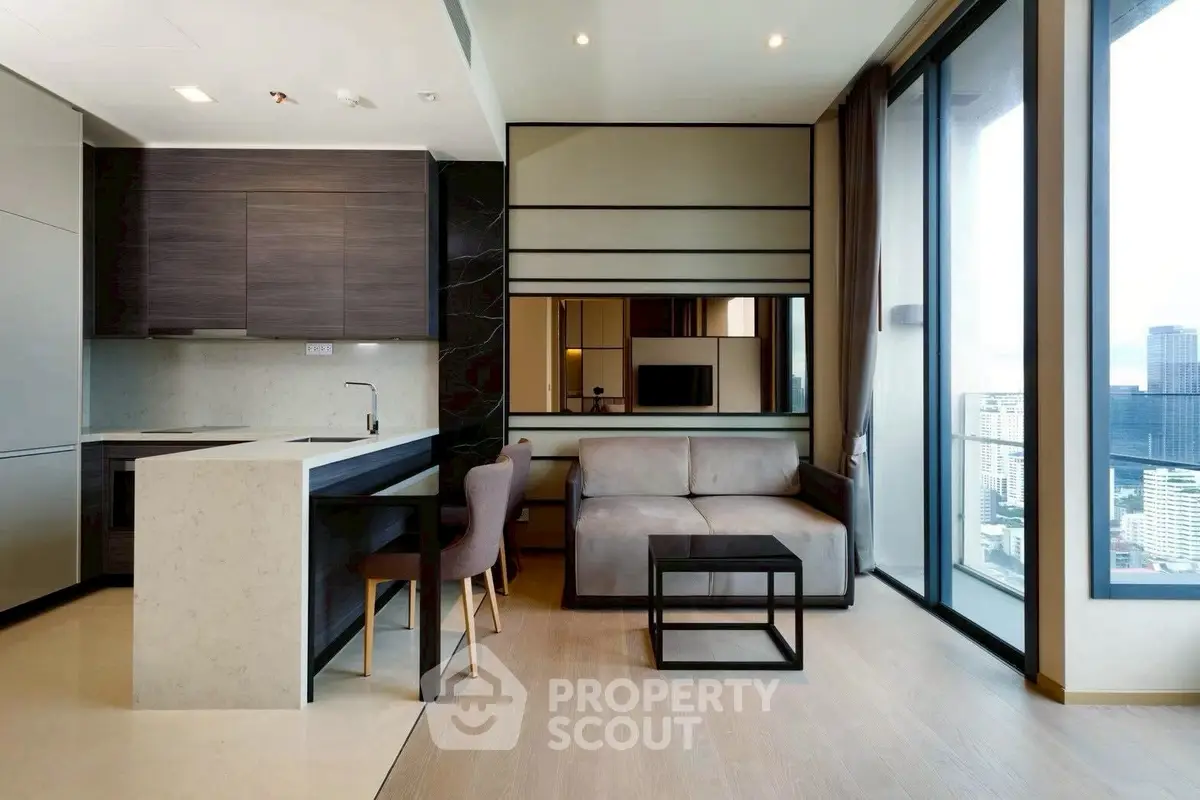 Modern open-layout living room with kitchen and stunning city view from large windows.