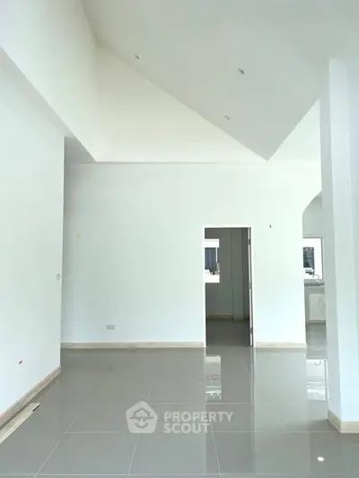 Spacious modern interior with high ceilings and sleek tile flooring, perfect for customization.
