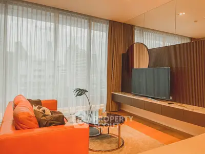 Modern living room with stylish decor and large TV, featuring a sleek orange sofa and floor-to-ceiling windows.