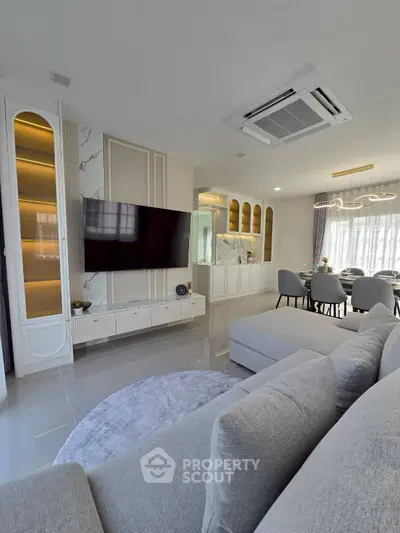 Modern living room with elegant decor and open dining area, featuring sleek furniture and ambient lighting.