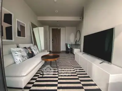 Modern living room with stylish decor and large TV, featuring a cozy sofa and striped rug.