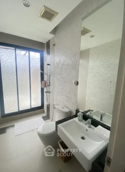 Modern bathroom with sleek fixtures and large frosted window for natural light.