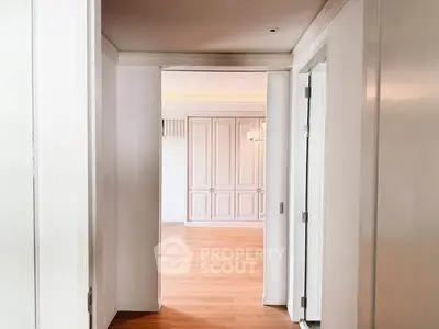 Elegant hallway leading to a spacious living area with wooden flooring and stylish paneling.