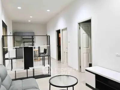 Modern open-plan living room with sleek furniture and kitchen in background