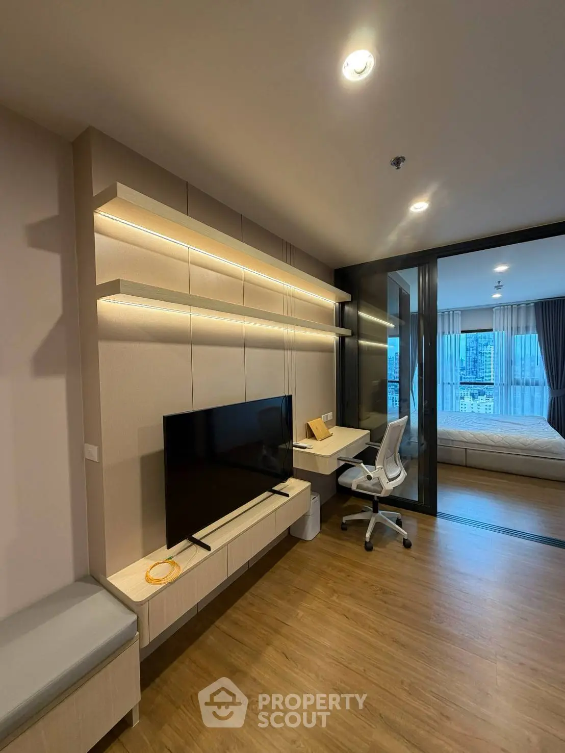 Modern living room with sleek TV setup and cozy workspace in stylish apartment