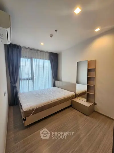 Modern bedroom with large window and minimalist decor in a high-rise apartment.