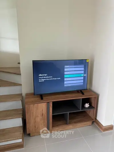 Modern living room with sleek TV stand and staircase, perfect for contemporary home decor.