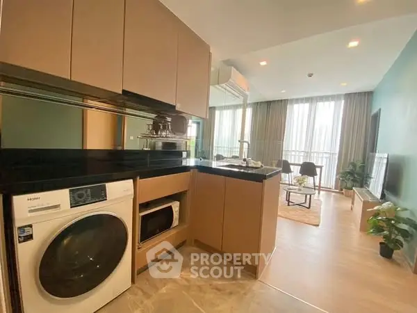 Modern open kitchen with washing machine and cozy living area in stylish apartment