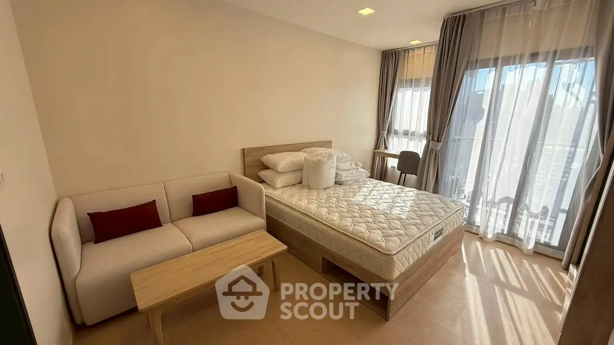 Modern bedroom with natural light, featuring a cozy sofa and a comfortable bed, ideal for relaxation.