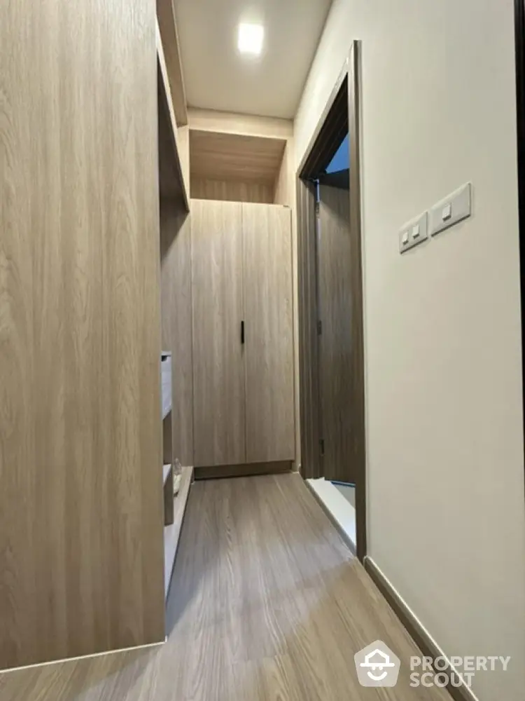 Modern hallway with sleek wooden flooring and built-in storage cabinets