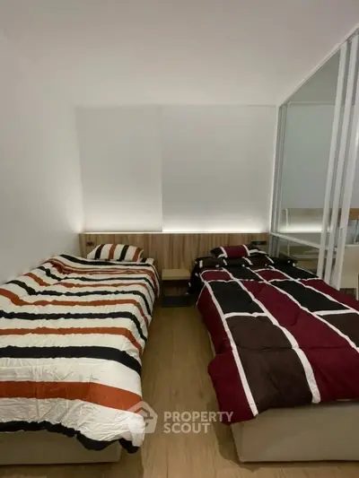 Modern bedroom with twin beds and stylish bedding in a cozy apartment.