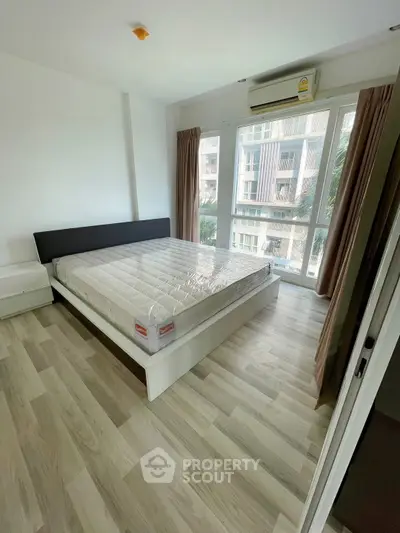 Spacious bedroom with large windows and modern flooring in a high-rise apartment.