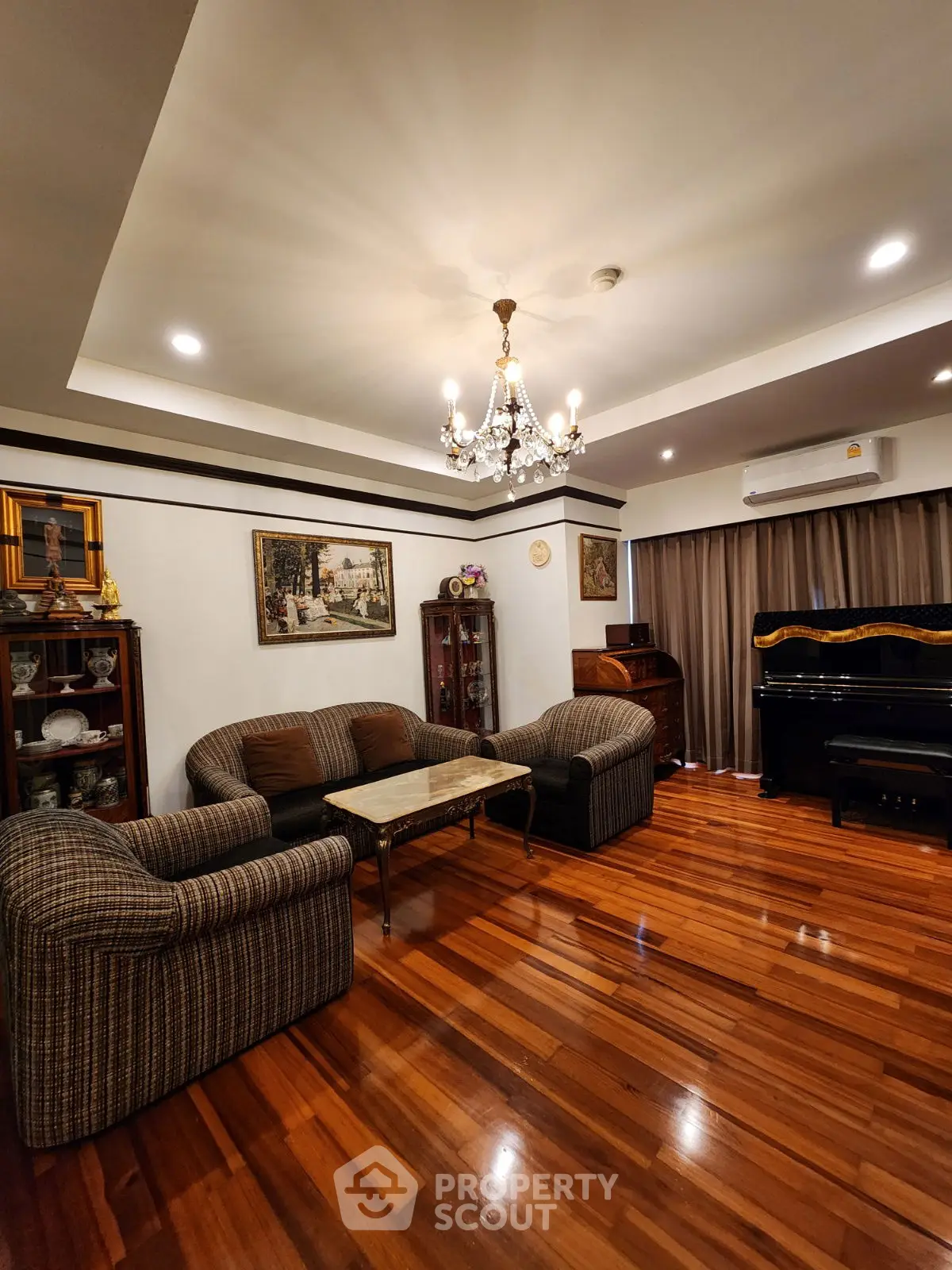 Elegant living room with chandelier, polished wood floors, and classic furniture.