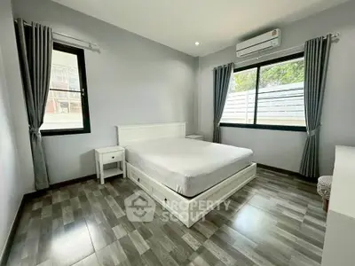 Spacious bedroom with modern decor and large windows for natural light.