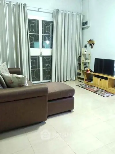 Cozy living room with modern sofa and entertainment center, featuring elegant curtains and bright flooring.