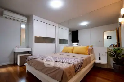 Modern bedroom with mirrored wall and stylish decor in a cozy apartment.