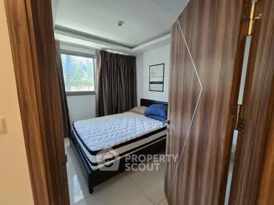 Cozy bedroom with modern decor and natural light through window.