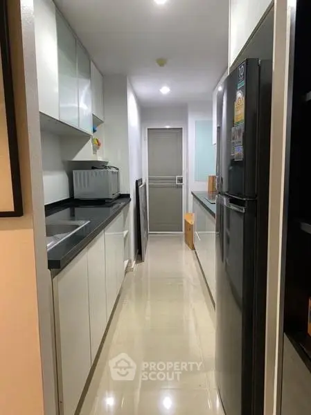 Modern kitchen with sleek cabinets and stainless steel appliances in a narrow layout.