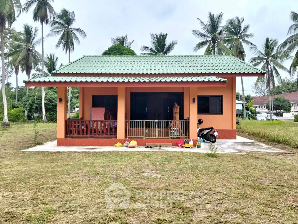 Charming tropical bungalow with green roof and spacious front yard, surrounded by palm trees.