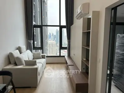Modern living room with city view, featuring sleek furniture and large windows in a high-rise apartment.