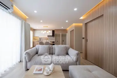 Modern living room with cozy sofa and open kitchen layout, featuring elegant lighting and wooden accents.